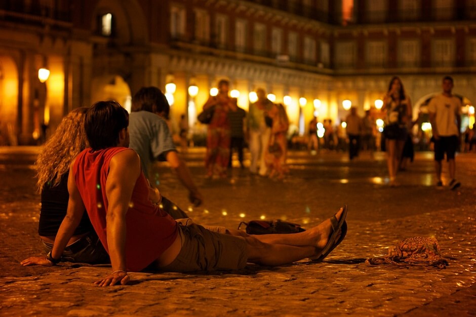 Jeunes gens assis sur le sol d'une place à Madrid.