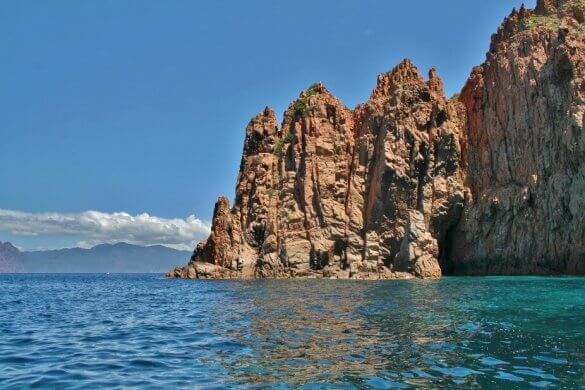 Vue d'une falaise rose plongeant dans la mer en Corse.