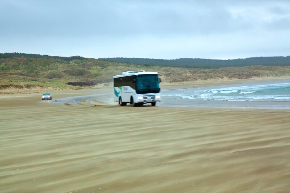 Vue d'un bus roulant sur une plage en Nouvelle-Zélande.