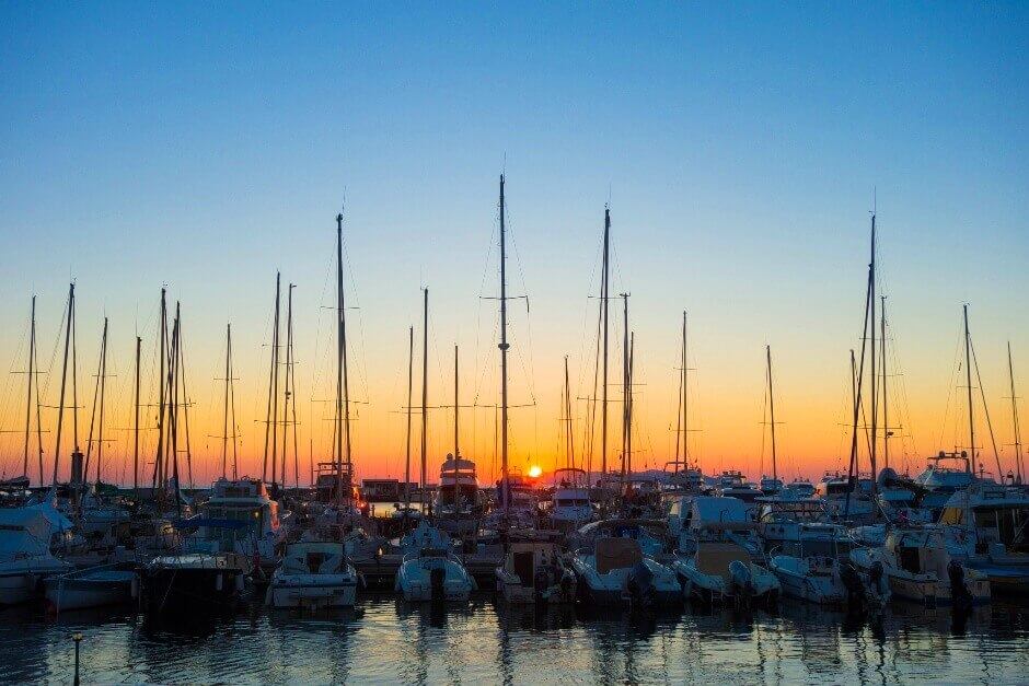 Vue d'un lever de soleil à travers les mâts de bateaux en Corse.