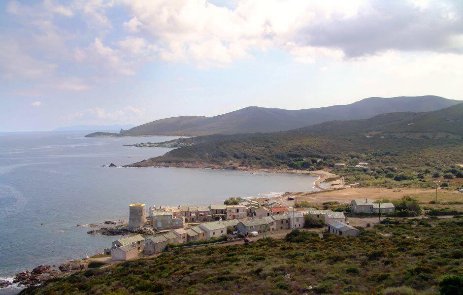 Vue plongeante sur un village corse au bord de la mer.