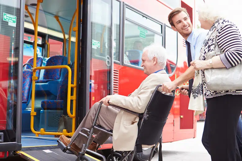 Un chauffeur de bus aide un homme en fauteuil roulant.