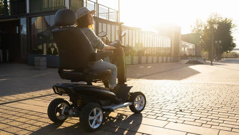 Une femme conduisant un fauteuil roulant électrique sur un terrain découvert.