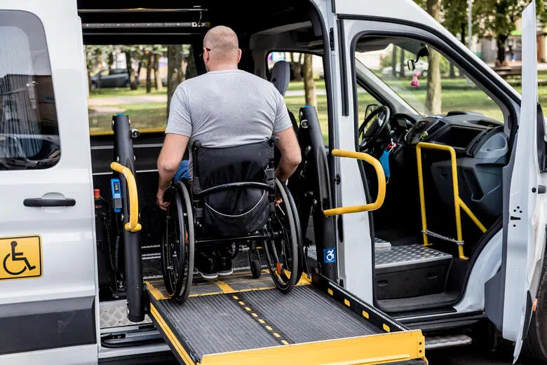 Une homme en fauteuil est soulevé par un lift dans une voiture de location.