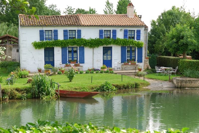 Vue d'une maison blanche au bord d'une petite rivière.